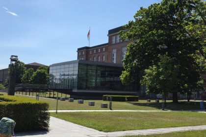 Landeshaus Kiel und gläserner Plenarsaal hinter einer Rasenfläche
