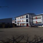 Schulgebäude mit leerem Schulhof und Sporthalle