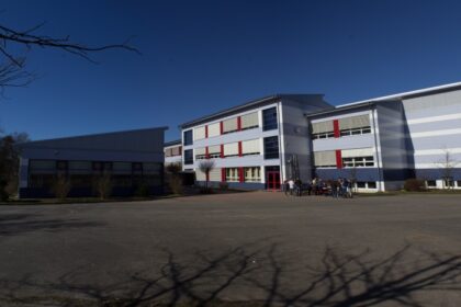 Schulgebäude mit leerem Schulhof und Sporthalle