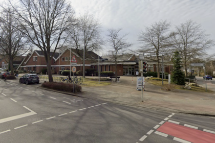 Straßenkreuzung mit Radfurt, Parkplätzen, Bäumen und flachen öffentlichen Gebäuden