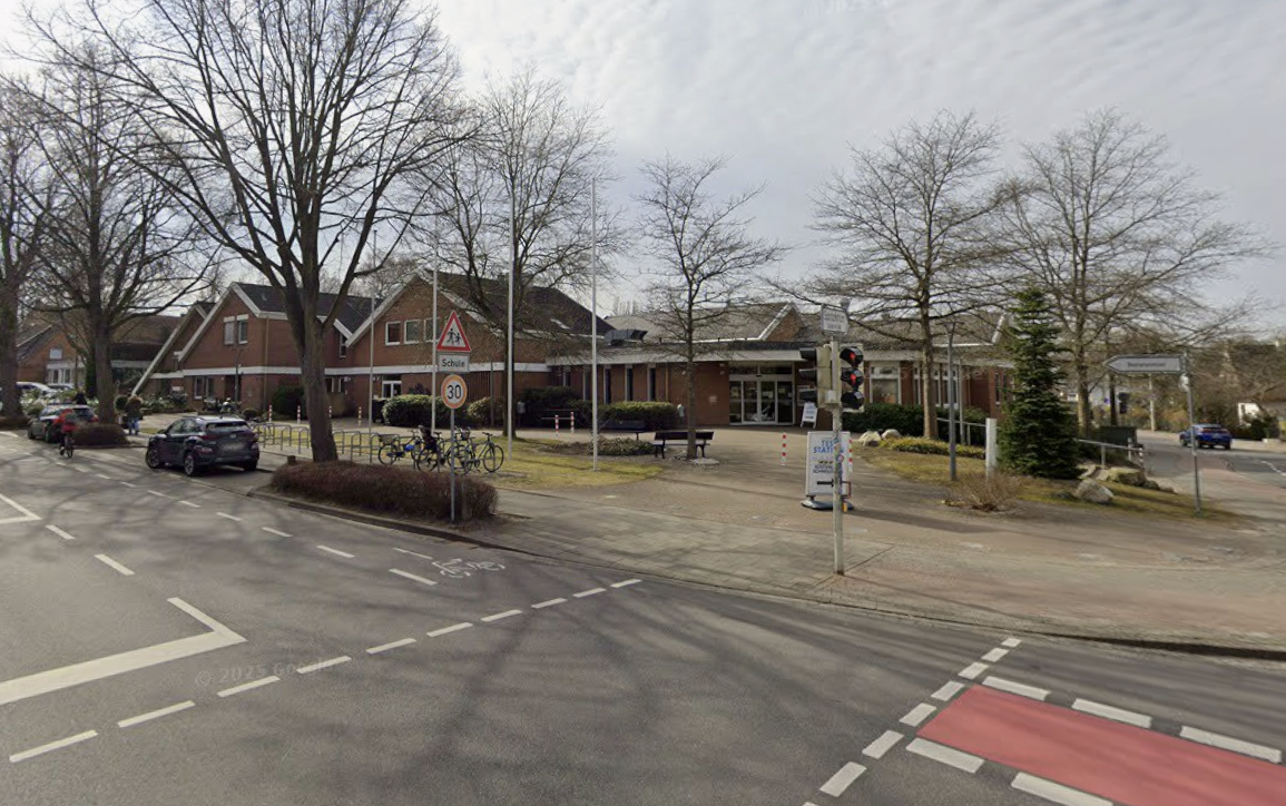 Straßenkreuzung mit Radfurt, Parkplätzen, Bäumen und flachen öffentlichen Gebäuden