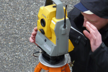 Vermesser arbeitet an einer gelben Totalstation