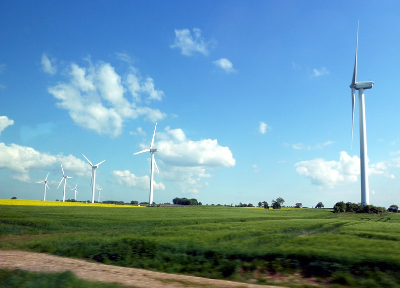 Mehrere Windenergieanlagen auf grünen Feldern unter blauem Himmel bei Fiefbergen