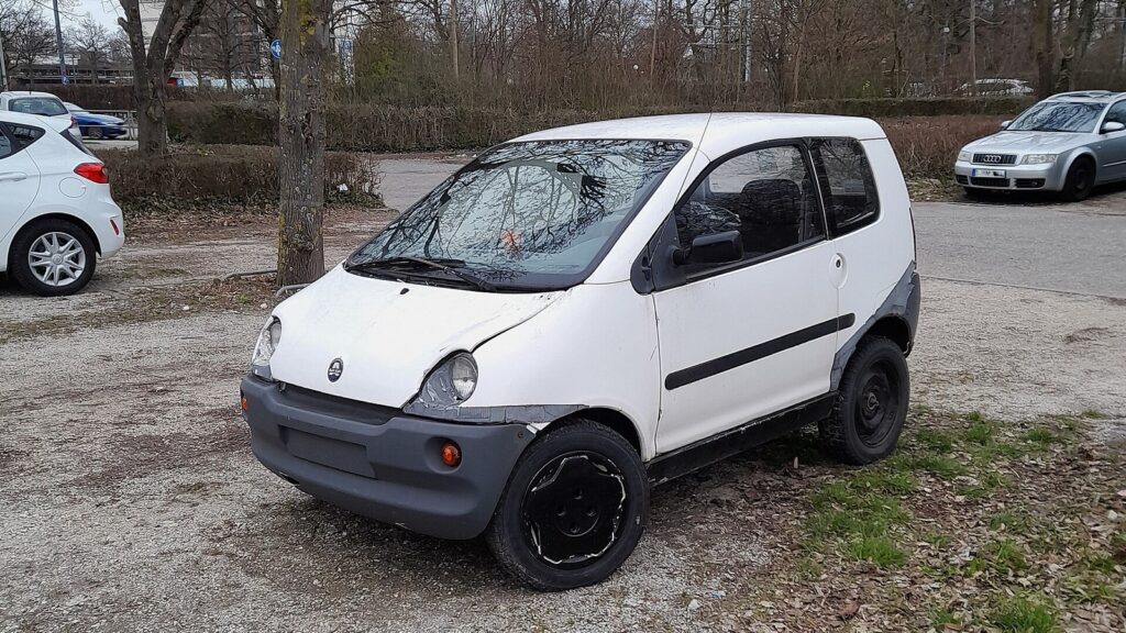 Kleines weißes vierrädriges Leichtkraftfahrzeug auf einem Parkplatz