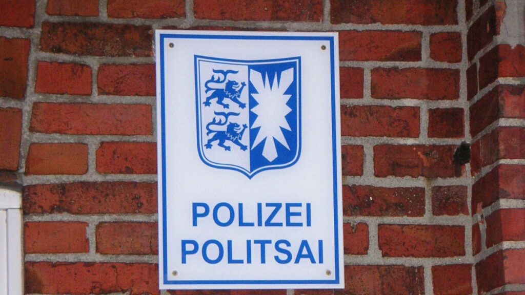 Polizeischild mit Landeswappen an einer Backsteinwand