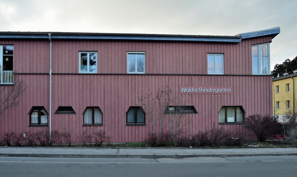 Holzgebäude eines Waldorfkindergartens mit Vorplatz